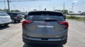 Rear view of a GMC Terrain SUV in a parking lot, with other cars and power lines overhead against a blue sky.