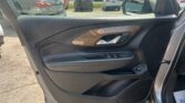 Interior of a car door with wood trim and control panel; view of a parking lot with several cars outside.