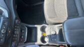 Center console of a car showing cup holders, gear shifter, and climate control buttons with part of the passenger seat nearby.