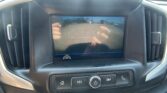 Car dashboard screen displaying the rearview camera feed with orange parking guide lines for reversing