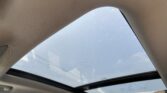 View from inside a car showing the panoramic sunroof with a blue sky and raindrops on the glass.