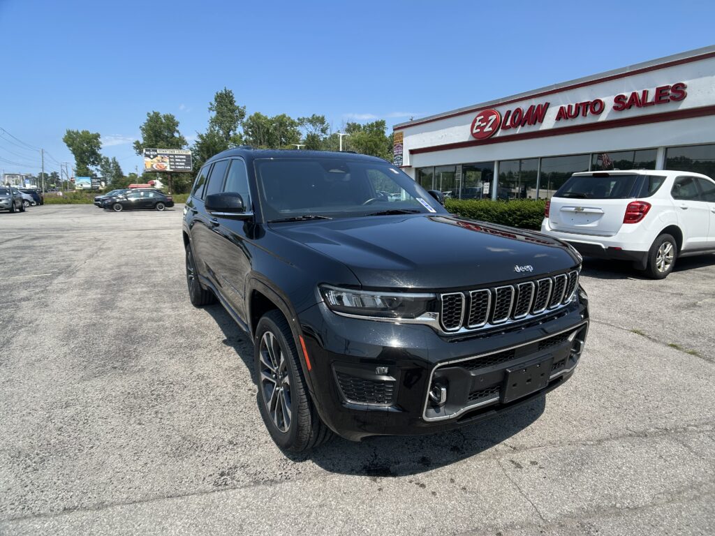 Black Jeep SUV in the foreground outside EZ Loan Auto Sales dealership with other cars and a blue sky behind it.]}]}}Oops; need proper JSON. Let's craft properly.