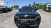 Front view of a black Jeep SUV in a car dealership lot with a blue sky and a LOAN Auto Sales sign in the background.