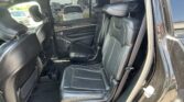 Interior of a dark SUV showing black leather captain chairs, headrests, and rear door panel