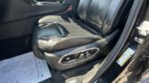 Dark leather car interior with front seats, center console, and visible seat controls.