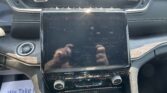 Center console with a tall touchscreen showing a map, radio controls, and app icons, beneath a row of physical buttons and vents.