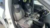 Front interior of a car showing driver and passenger seats with center console and gear shifter, dark upholstery with white stitching.