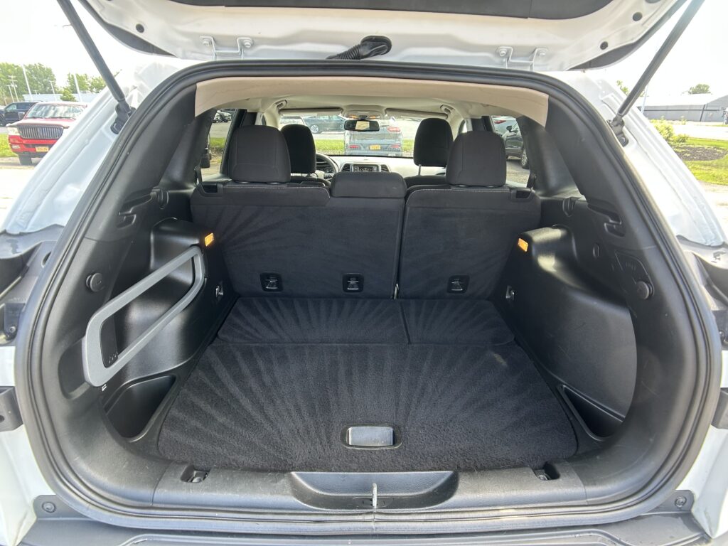 Open SUV trunk with rear seats upright and a spacious black carpeted cargo area.