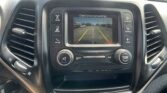 Infotainment screen shows the rearview camera with parking guidance lines (green/yellow/red) while reversing in a car interior.