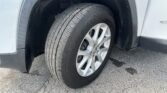 Close-up of a car wheel and tire in the wheel well area on asphalt surface, showing tread detail and rim.
