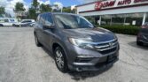 Gray Honda SUV parked in front of EZ Loan Auto Sales storefront on a sunny day with other cars and trees in the background.