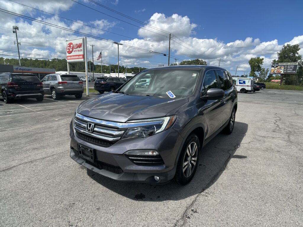 Gray Honda SUV in a car dealership lot with other vehicles and an E-Z Loan Auto Sales sign nearby