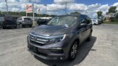 Gray Honda SUV in a car dealership lot with other vehicles and an E-Z Loan Auto Sales sign nearby
