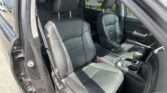 Open car door reveals black leather front seats and center console in a sunlit vehicle interior