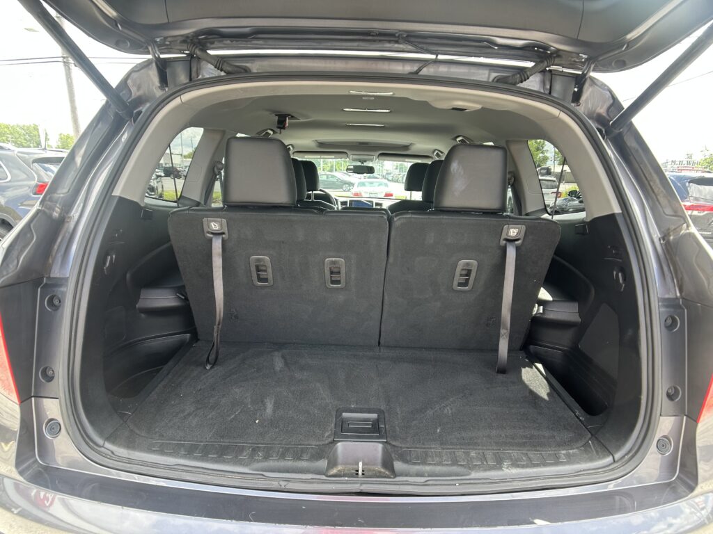 SUV with rear hatch open showing trunk and folded third-row seats, empty cargo area