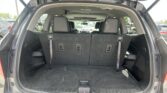SUV with rear hatch open showing trunk and folded third-row seats, empty cargo area