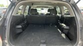 Open SUV hatch showing a spacious black cargo area with second-row seats upright; view of parked cars outside through the rear window.