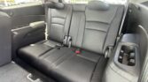 Back row of black leather car seats with three headrests and visible seat belts (interior of SUV).