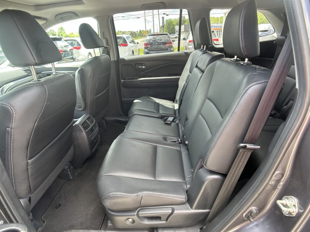 Black leather rear passenger seating in an SUV, with headrests, seat belts, and rear climate vent visible.