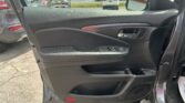Inside of a car door: black textured panel, chrome door handle, window controls, and a red reflector at the bottom.