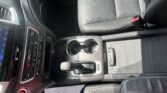 Interior of a car showing the center console with cup holders, gear shifter, and passenger seat belt buckle nearby.