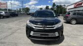 Front view of a black SUV parked in a dealership lot, with an E-Z LOAN building on the right and other cars around.