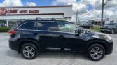 Black SUV in the foreground at an auto dealership with an EZ LOAN AUTO SALES sign and a Toyota showroom in the background on a sunny day.