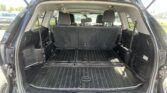 Open SUV cargo area with rear seats upright and a black rubber cargo mat, showing spacious trunk.