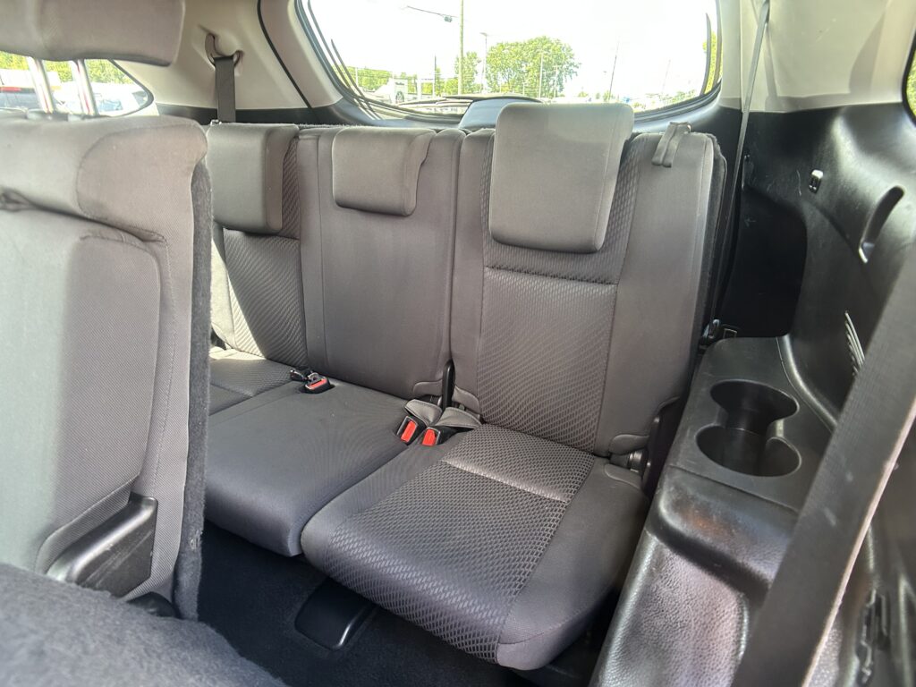 Rear row of a dark fabric SUV seats with three seating positions and visible seatbelts