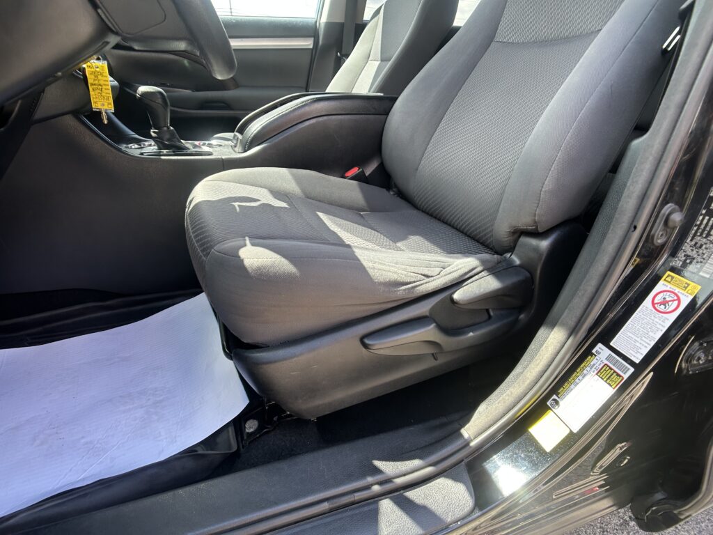Interior of a car with front seats, center console, gear shifter, and a yellow key tag hanging from the ignition in view