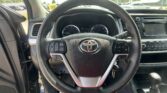 Close-up of a Toyota steering wheel with instrument cluster, center console, and touchscreen in a car interior.