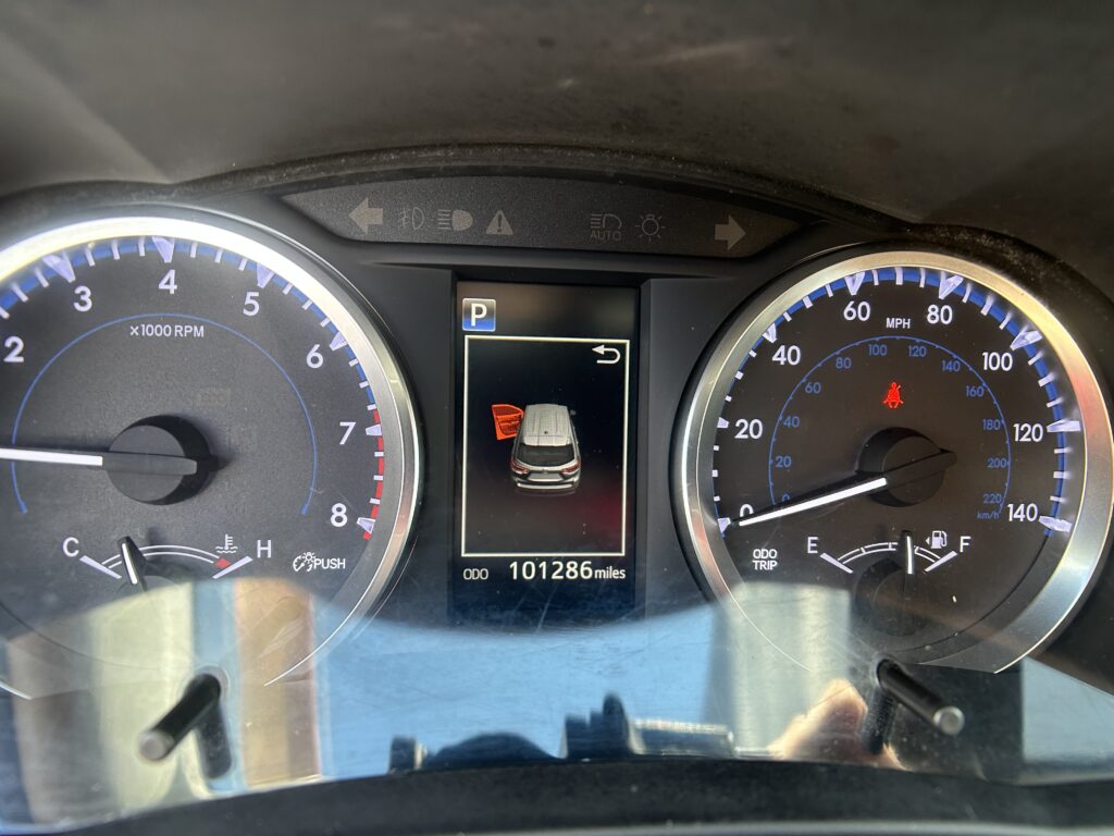Dashboard of a car showing speedometer and tachometer, center screen with 'P' gear and a vehicle graphic, odometer 101,286 miles.