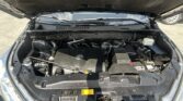 Open car hood revealing engine bay with Toyota emblem on engine cover; visible battery and fluid reservoirs.