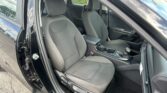 Interior of a car with two front gray cloth seats, center console, and gear shifter seen from an open door