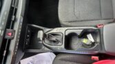 Interior of a car showing the center console with gear shifter, climate controls, and gray fabric seats in the front cabin.