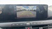 Car dashboard backup camera display showing parking lines: yellow center, red near, blue sky and lot ahead; text says 'Check surroundings for your safety' (informational image).