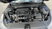 Open car hood reveals the engine bay with a DOHC 16V engine cover at center and various hoses, wires, and components surrounding it.