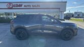 Grayscale SUV parked in front of a white car dealership sign that reads E-Z LOAN AUTO SALES on a sunny day
