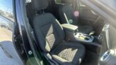 Interior of a car showroom model: front seats, center console, and dashboard visible through an open door with sunlight flare.