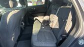 Rear seat area of a dark fabric SUV with three seats, headrests, and visible seat belts; sunlight through the windows.
