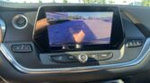Infotainment screen showing the car's rearview camera feed with orange parking guidelines over a parking lot behind the vehicle