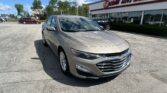 Silver Chevrolet sedan parked diagonally in front of EZ Loan Auto Sales storefront under a blue sky.