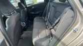 Interior of a car's rear seats in black fabric, showing three seating positions with seat belts and headrests, and a door panel nearby