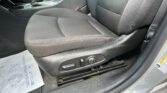 Driver's seat and center console area with seat adjustment controls and a visible seat belt in a dark car interior.