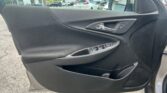 Driver-side car door interior with chrome handle and window controls; dealership lot visible through window.