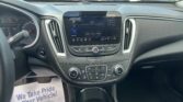 Car interior with center touchscreen displaying radio; a paper sign on the floor reads 'We Take Pride In Your Vehicle'.
