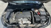 Open car hood showing engine bay with Ecotec engine cover, windshield wipers, and various hoses and reservoirs visible.