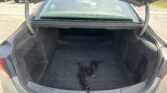 Open car trunk with dark carpeted cargo area and a black elastic cargo net on the floor