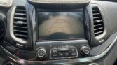 Center console with a car's touchscreen showing the rearview camera guidelines for parking, flanked by air vents and control buttons.