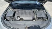 Open car hood showing the engine bay with a black plastic engine cover bearing the Chevrolet emblem.